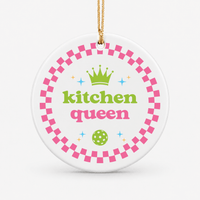 Round ceramic pickleball ornament that says kitchen queen with pink checkered border